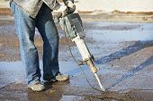 picture of construction  - Builder worker with pneumatic hammer drill equipment breaking asphalt at construction road works - JPG 